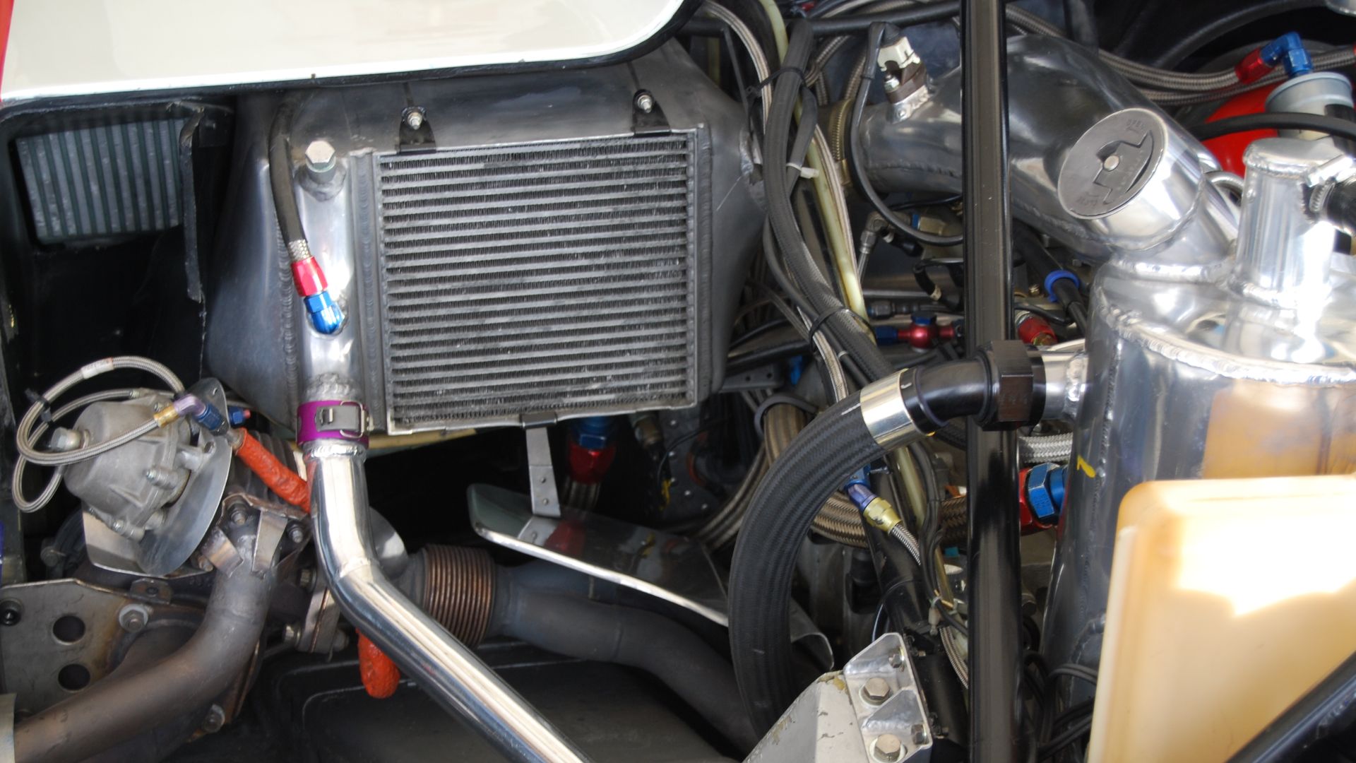 Boy oh boy is this a bunch of interesting stuff! Left to right, from the middle, we have left left (port) side of the car, with Rothman's red-white-blue-gold colors, the turbo exhaust and waste gate exhaust pipes, differential pressure diaphragm and actua