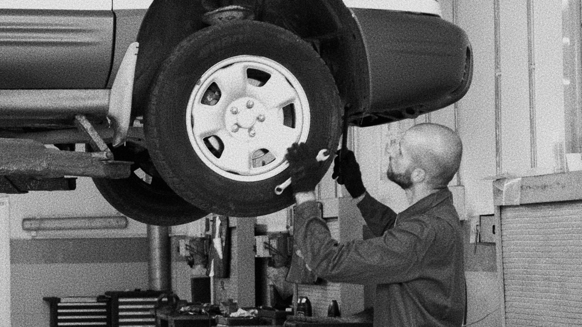 A mechanic examines an elevated car in a well-equipped auto repair shop.
