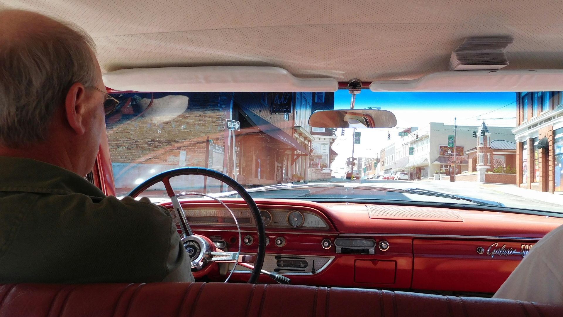 a man driving a red car down a street