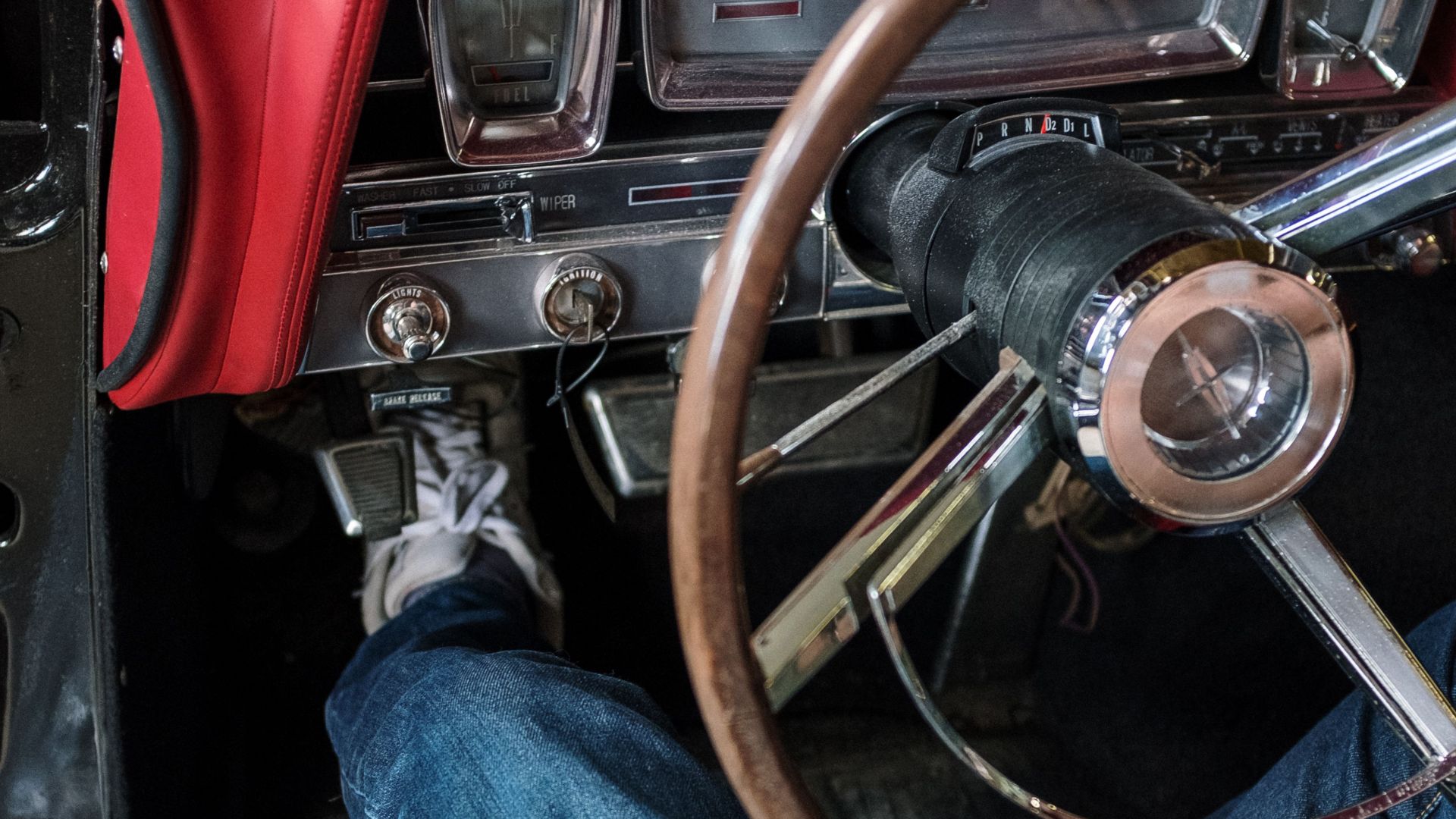Close-up of a person driving a vintage car. Focus on the retro dashboard and steering wheel.