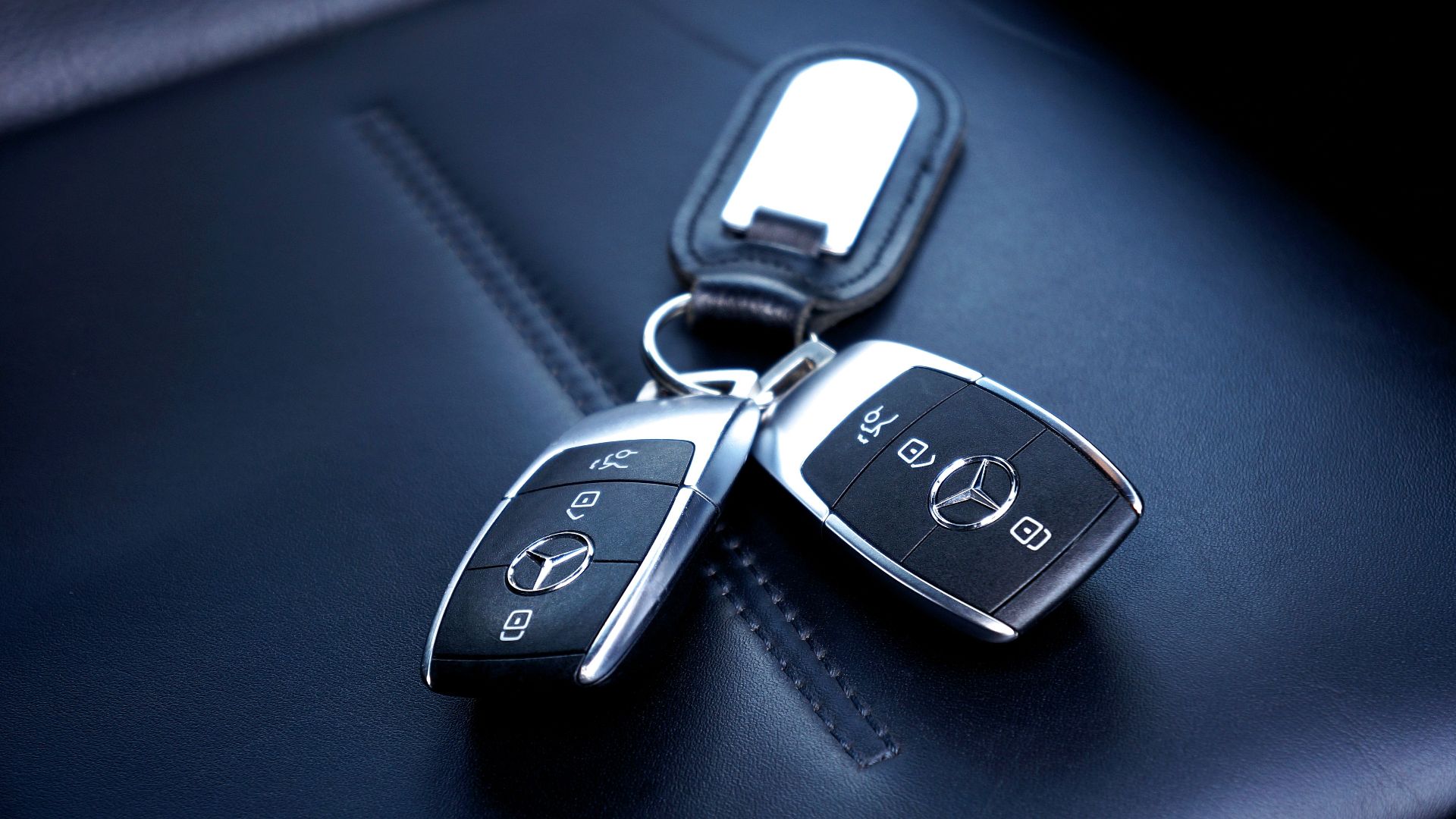 Two Mercedes Benz car keys resting on a luxurious leather seat, showcasing elegance and design.