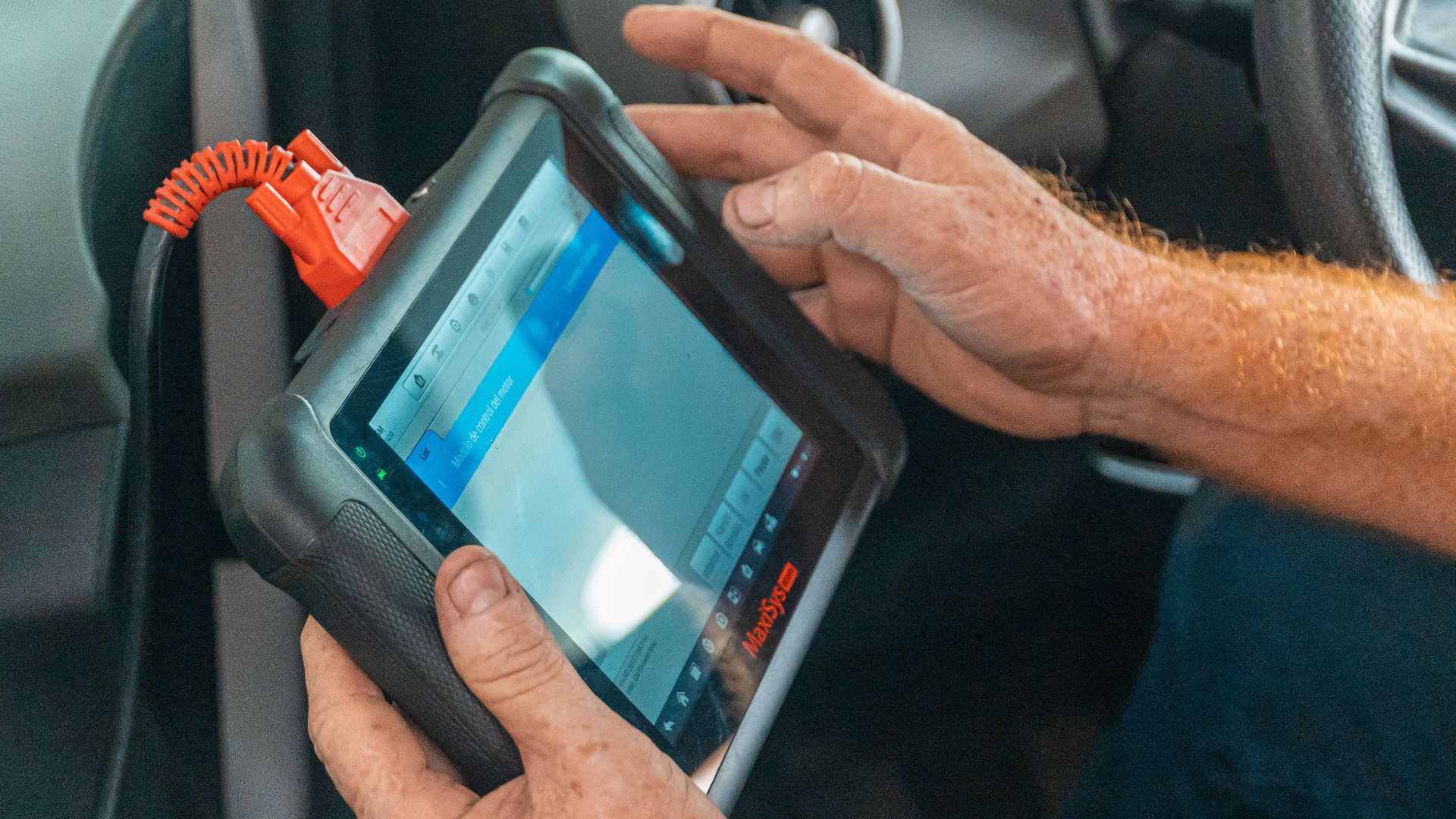 A mechanic uses a diagnostic tablet inside a car for vehicle analysis.