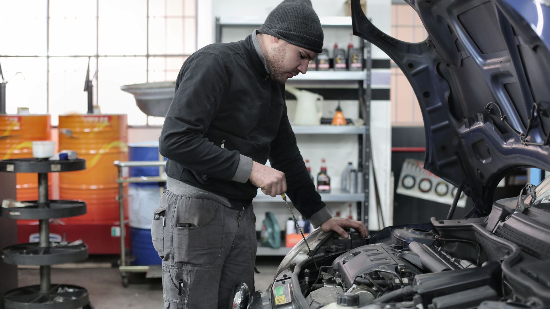 Mechanic checking a car engine in a garage, ensuring quality maintenance and repair.