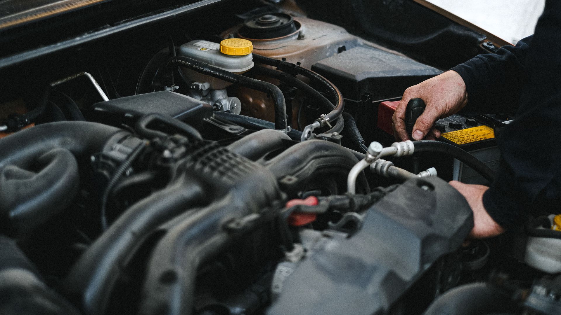 Close-up of a mechanic's hands working on a car engine, showcasing repair work.