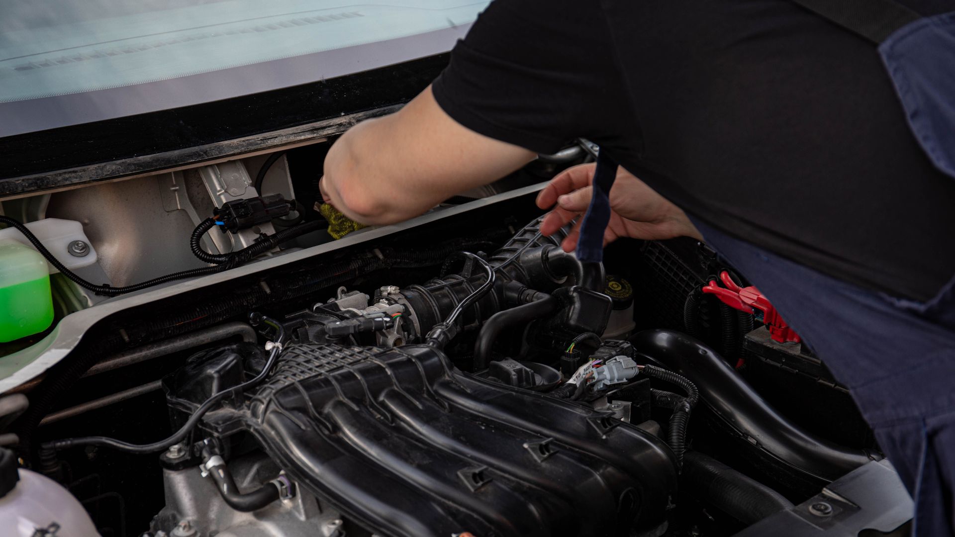 Close-up of a mechanic working on car engine. Ideal for automotive maintenance and repair themes.