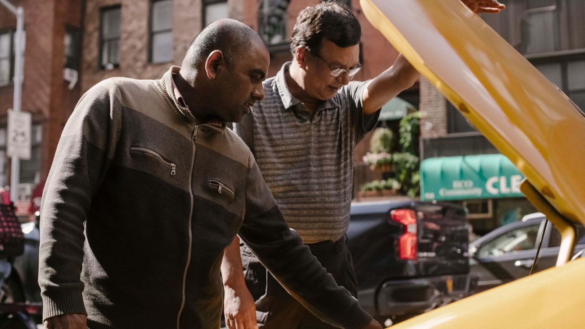 Focused multiracial male friends in casual clothes standing near opened hood of vehicle and looking at details