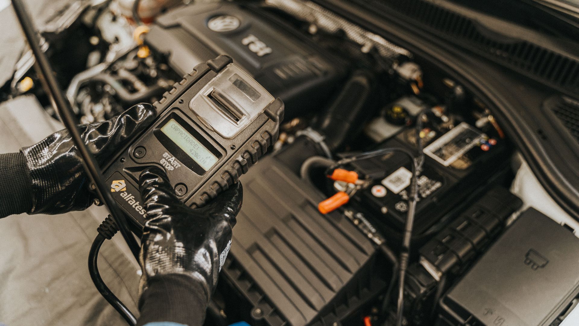 Mechanic diagnosing a car engine with a diagnostic tool, showcasing technical expertise and automotive care.