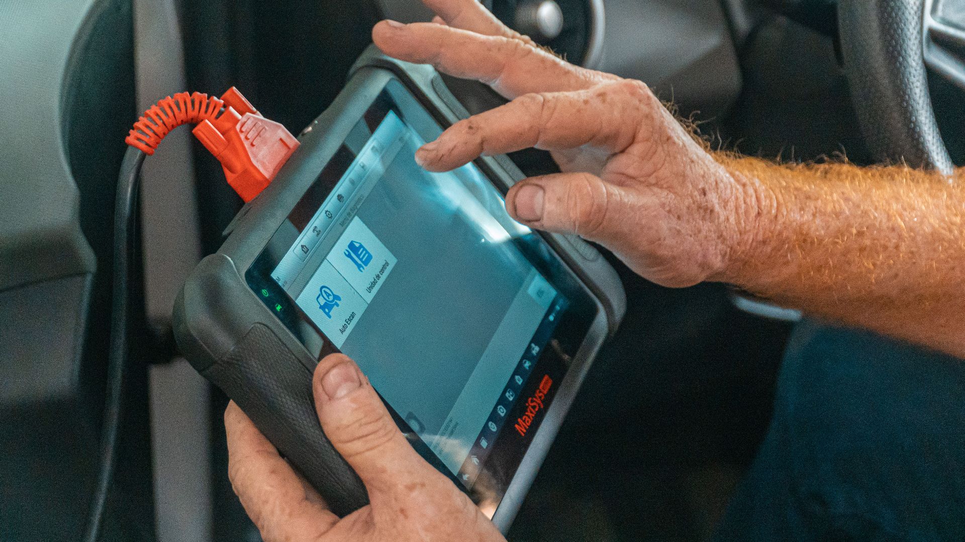 Mechanic using a diagnostic tool inside a car to check for engine issues and ensure proper maintenance.