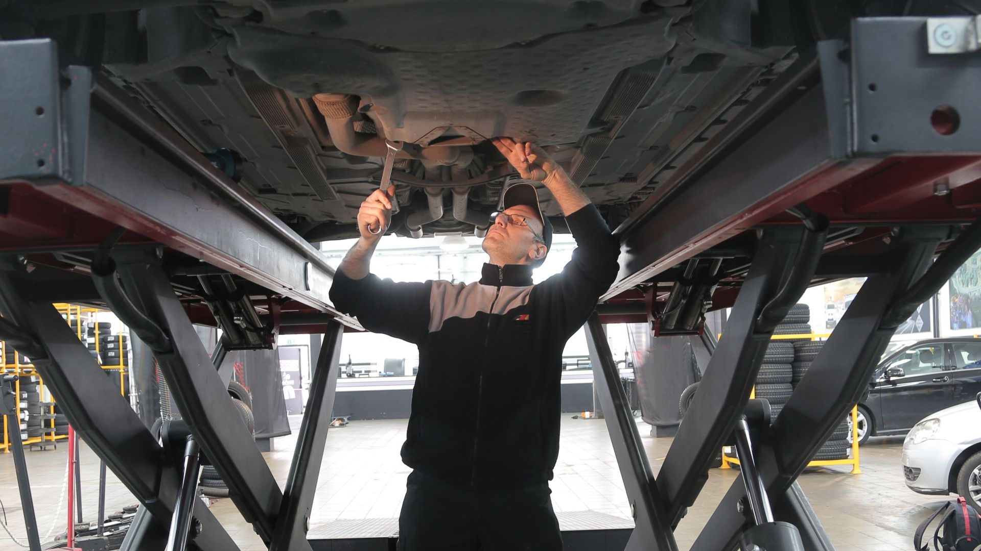 Mechanic inspecting and repairing a vehicle in a professional auto garage.