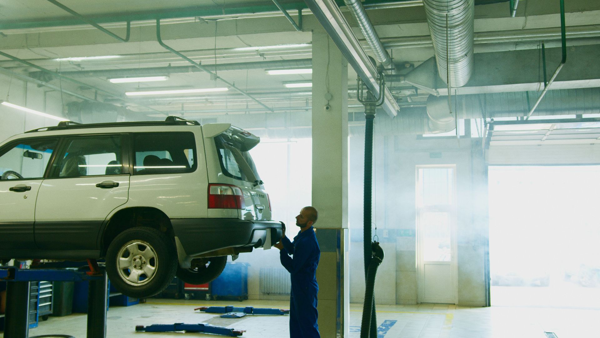Mechanic conducts vehicle inspection in an automotive garage setting.