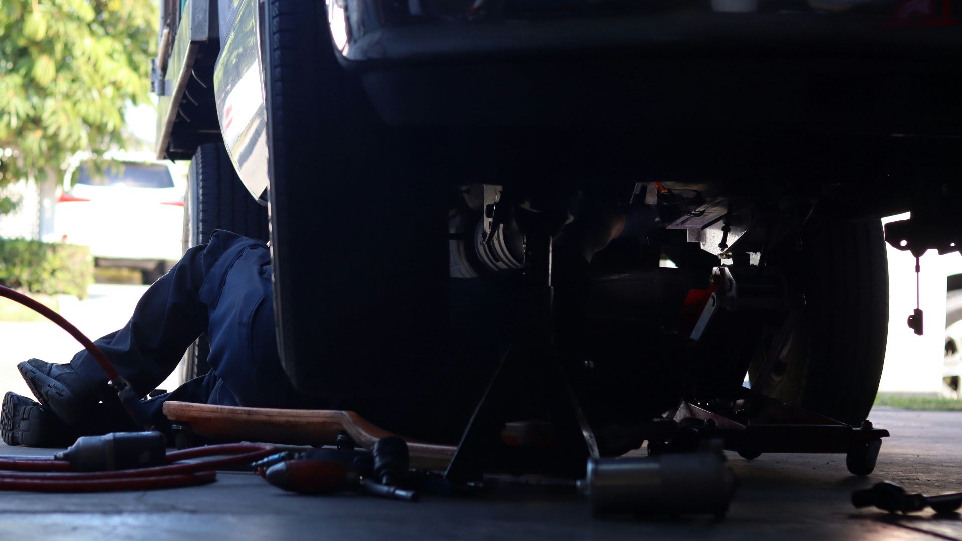 a man working on a vehicle under a truck