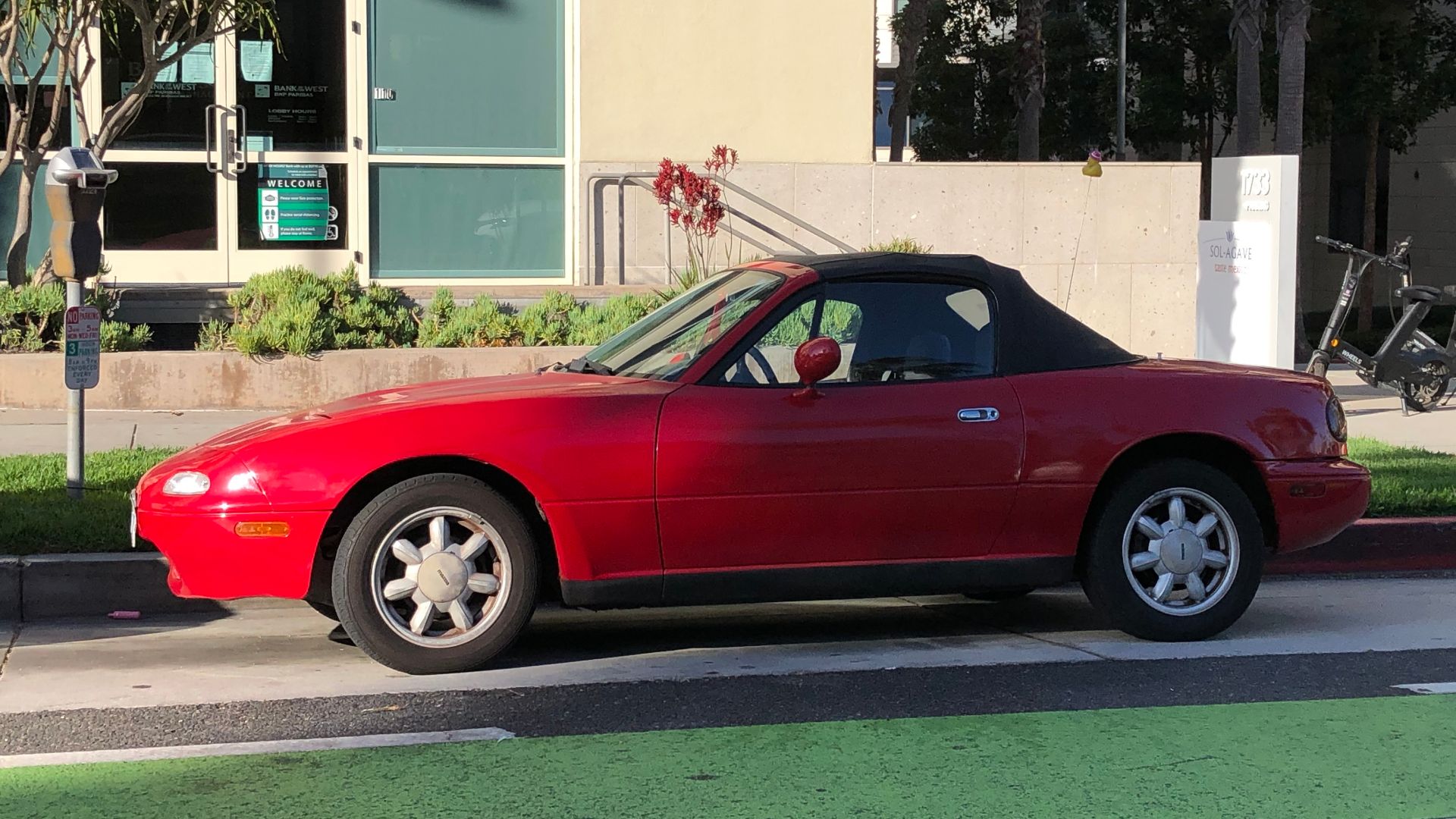 A red 1989–1997 Mazda MX-5 Miata convertible with a black soft-top roof.