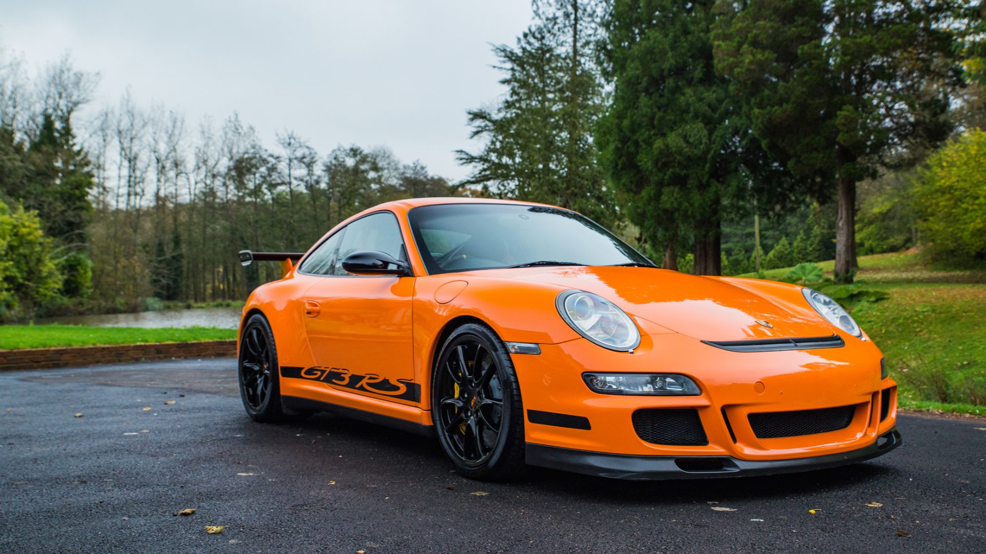 An orange 2006 Porsche 911 (997) GT3 RS 3.6 in a park.