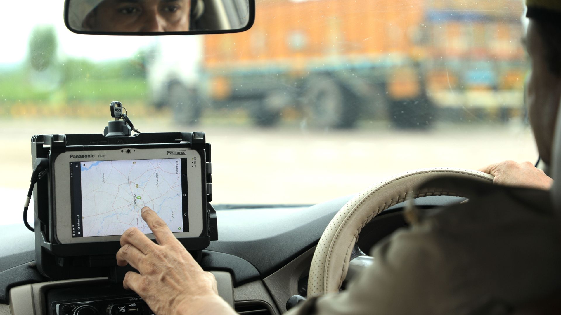 Police officer navigates using a digital map on a tablet inside a vehicle.