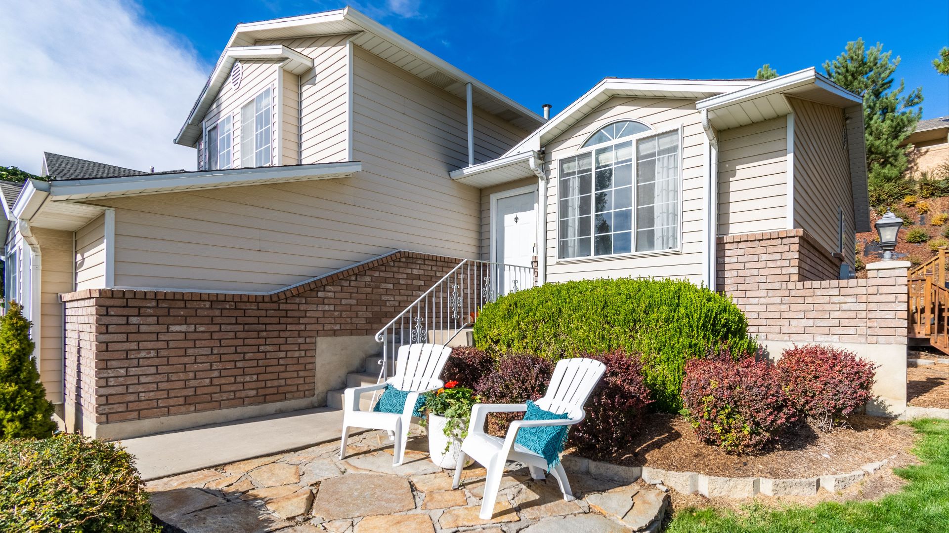 Elegant suburban house exterior with porch and seating area in bright daylight.
