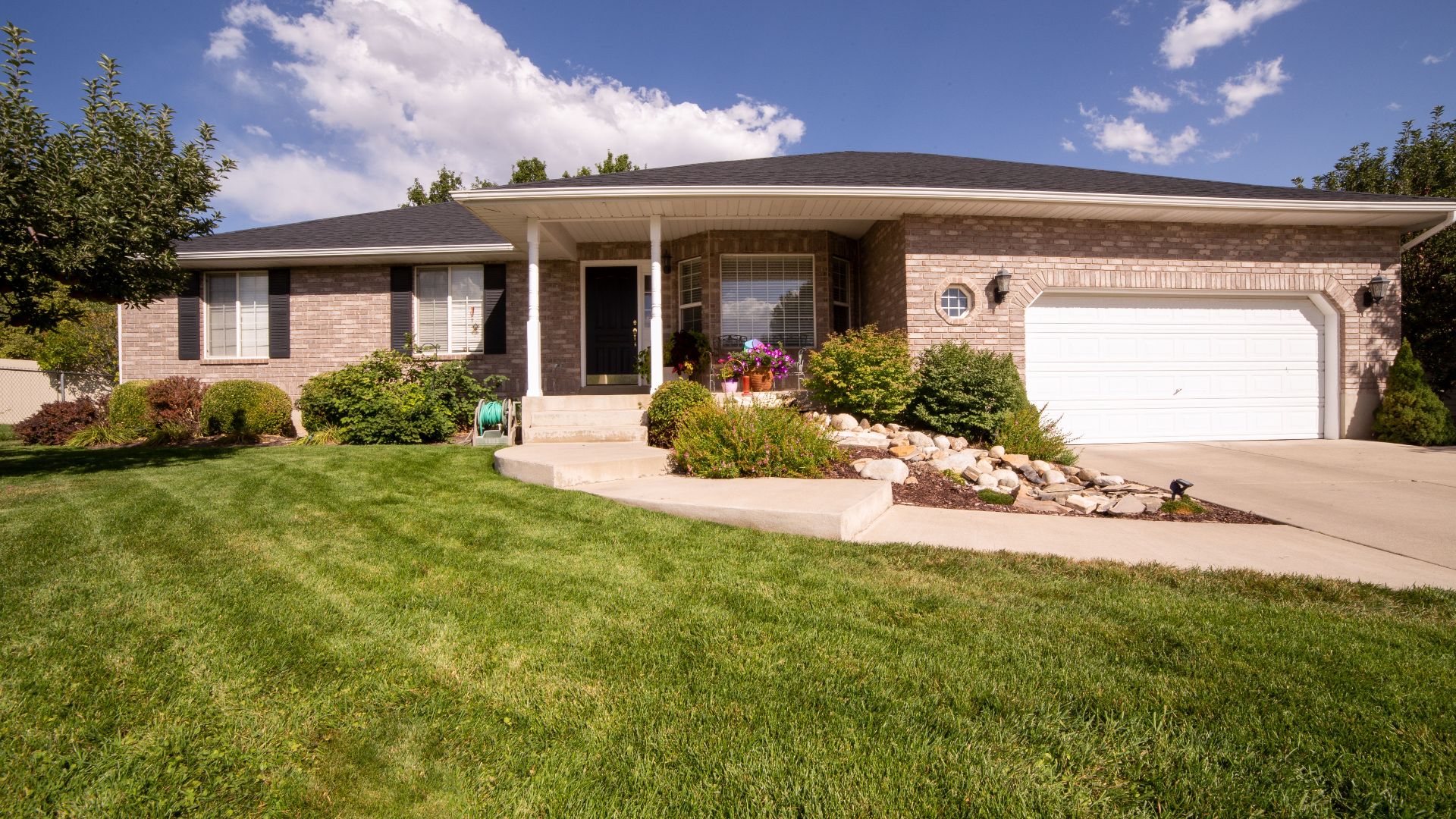 A modern suburban house exterior with a beautiful landscaped yard on a sunny day.