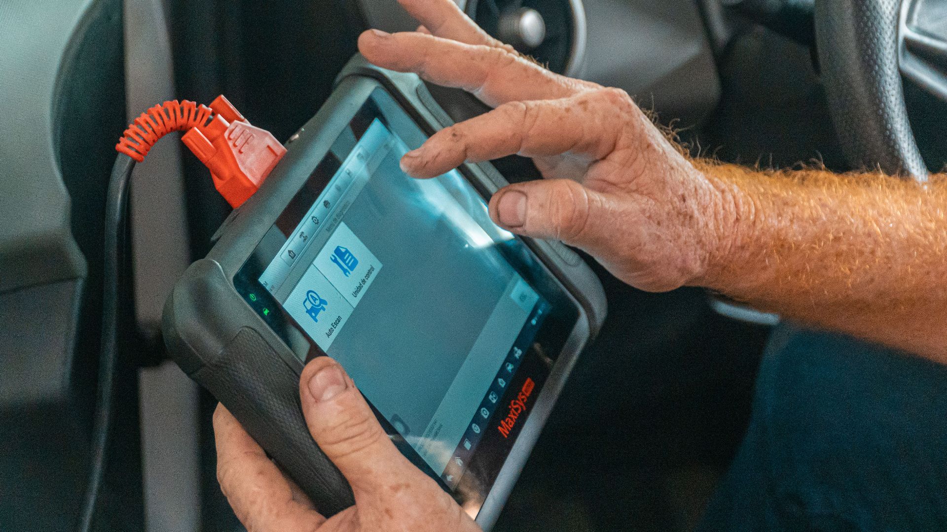 Mechanic using a diagnostic tool inside a car to check for engine issues and ensure proper maintenance.