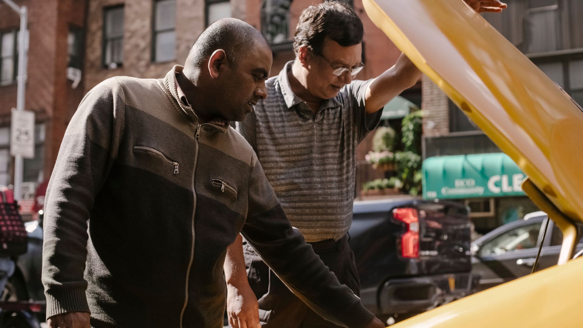Focused multiracial male friends in casual clothes standing near opened hood of vehicle and looking at details