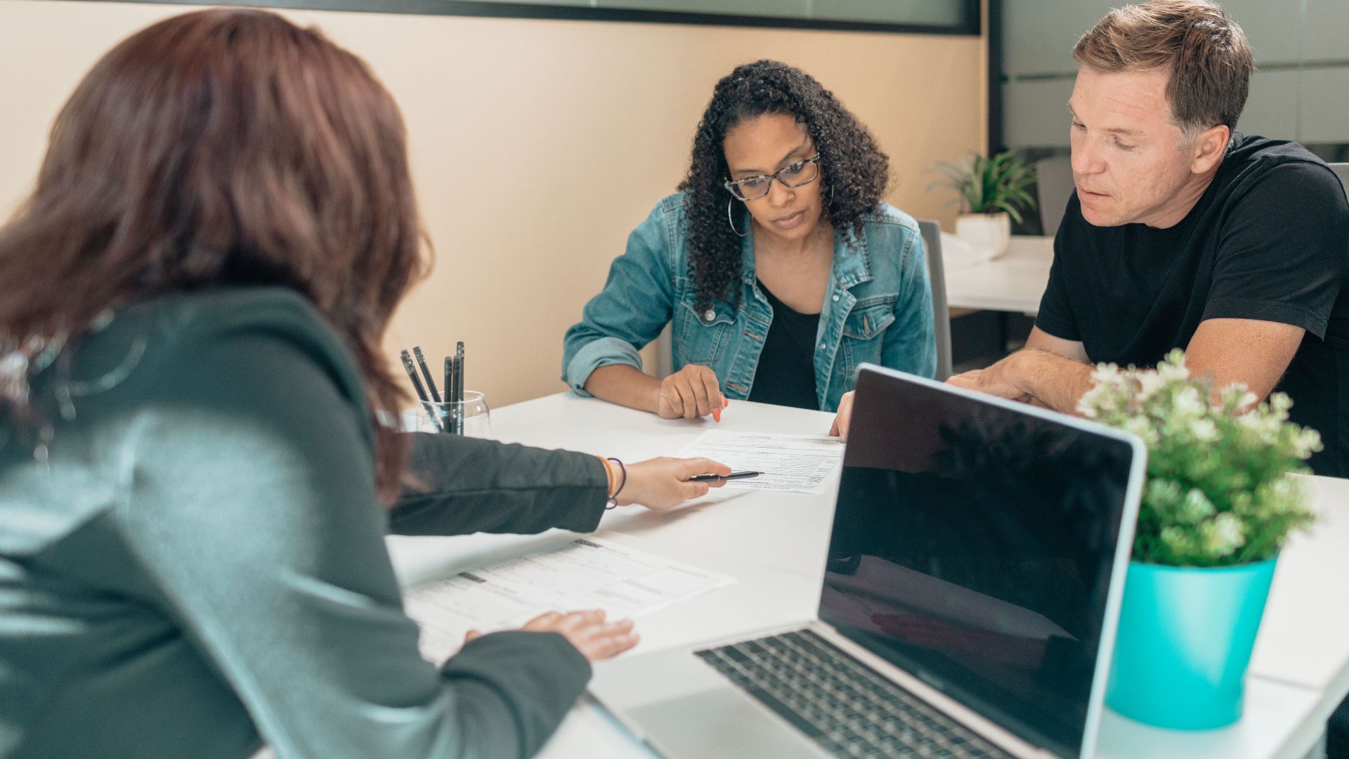 Couple meeting with advisor for adoption process in a modern office setting.