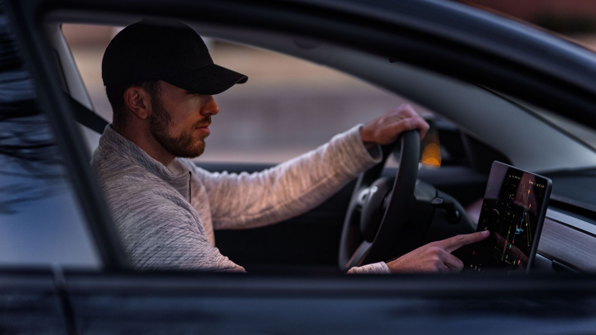 A man interacts with a touchscreen inside an electric car, driving through Dallas, TX.
