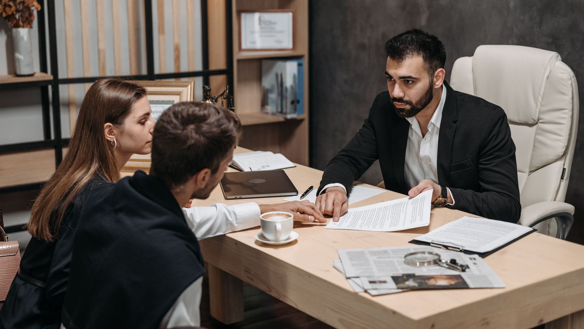 Lawyer discussing legal documents with clients at office desk.