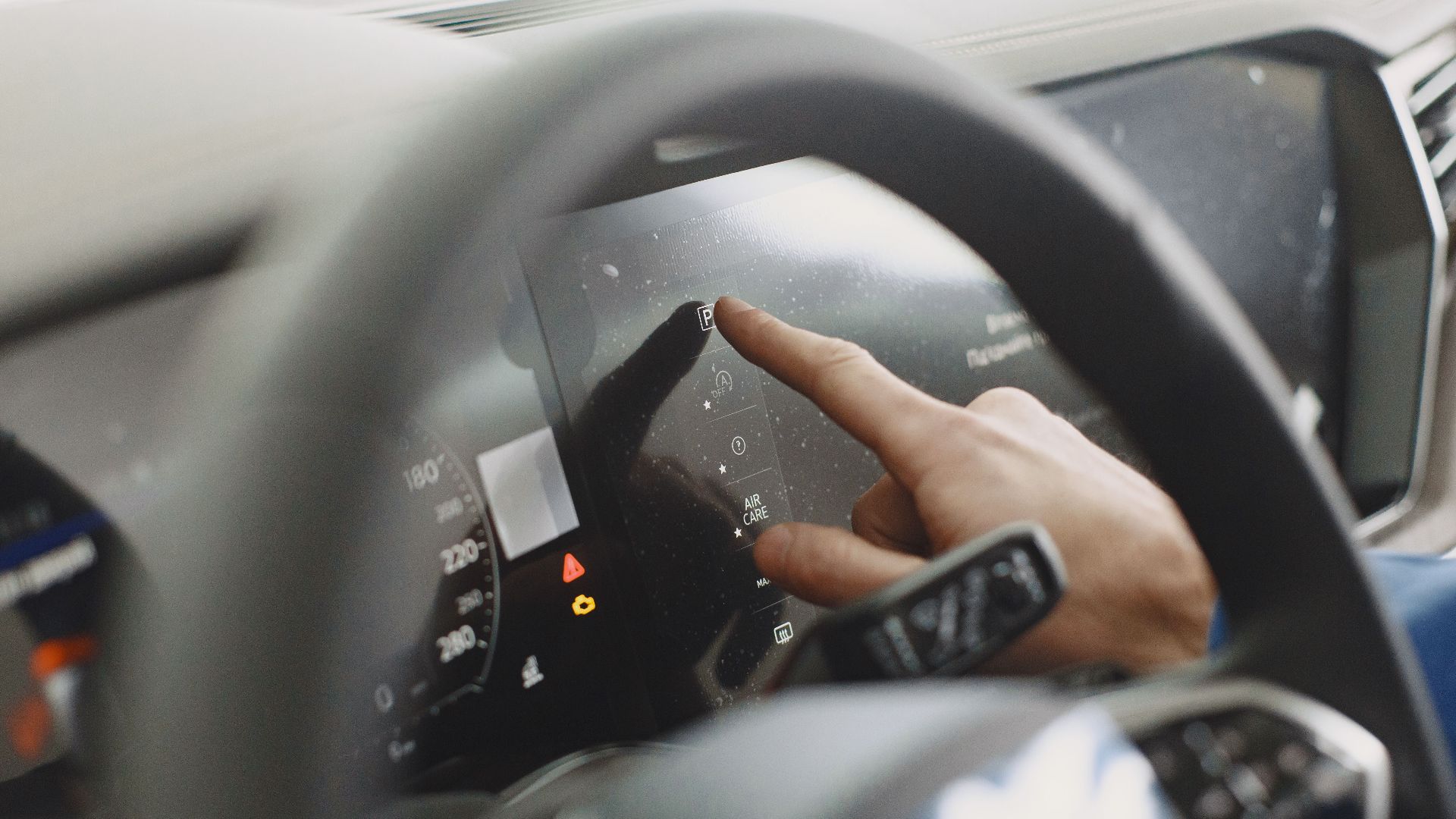 Close-up of a hand interacting with a car's digital dashboard. Modern technology and driving interface.