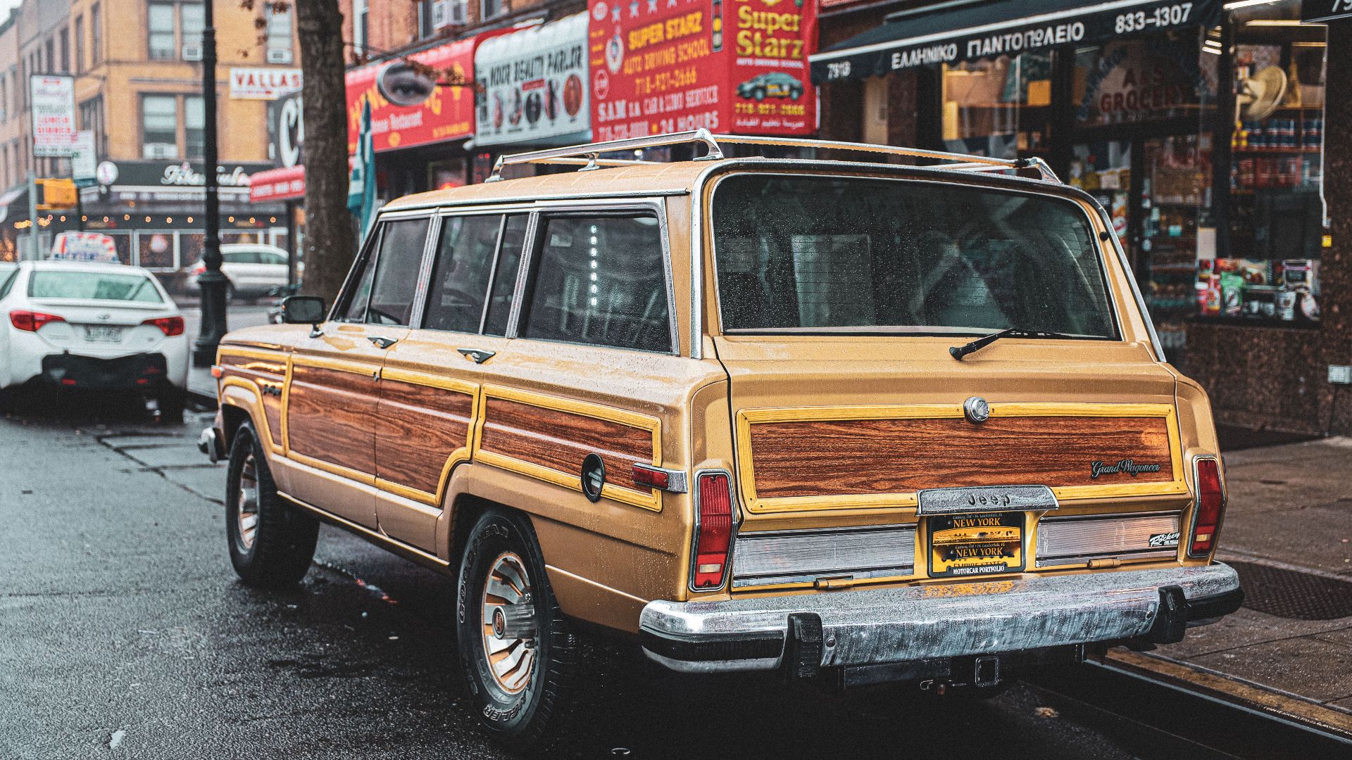 Classic vintage Wagoneer parked on a bustling city street with storefronts and urban vibe.