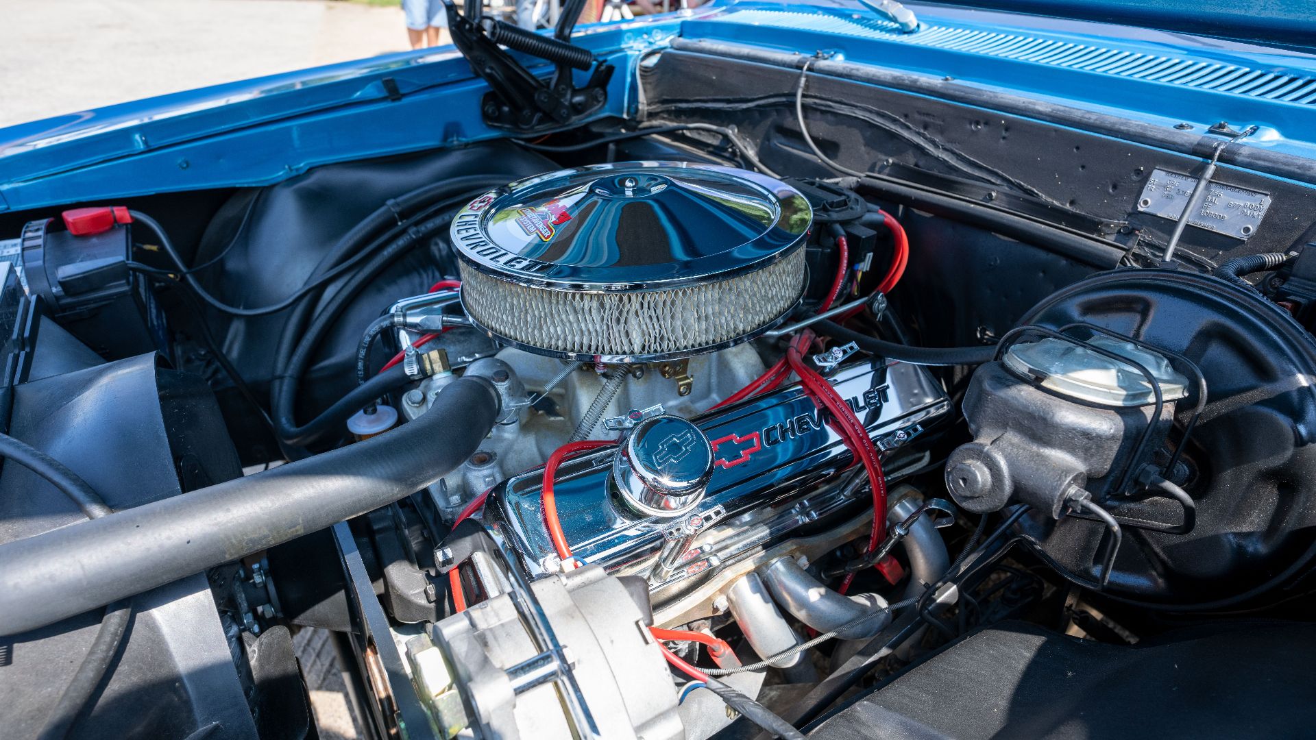 Detailed view of a Chevrolet car engine inside a classic vehicle's hood, blue exterior.