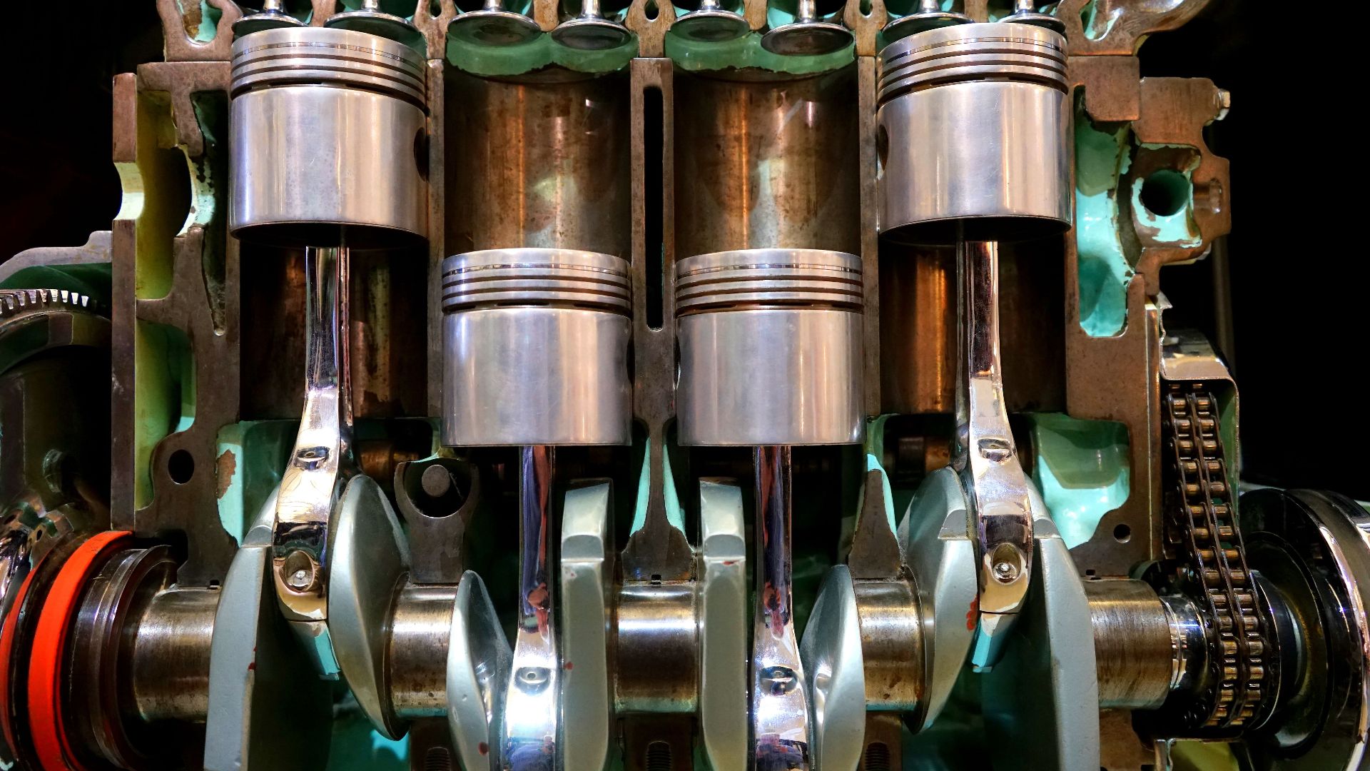 Close-up image of car engine pistons and crankshaft, showcasing mechanical components.