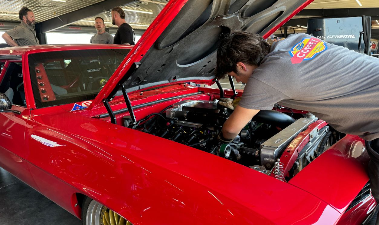 Car enthusiasts work on a classic red vehicle at a Nashville automotive event on October 12, 2024