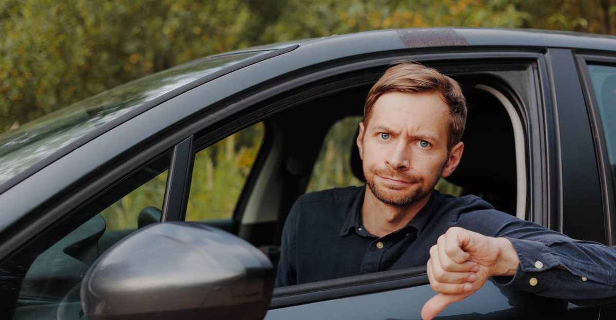 Unhappy driver showing thumbs down in car.