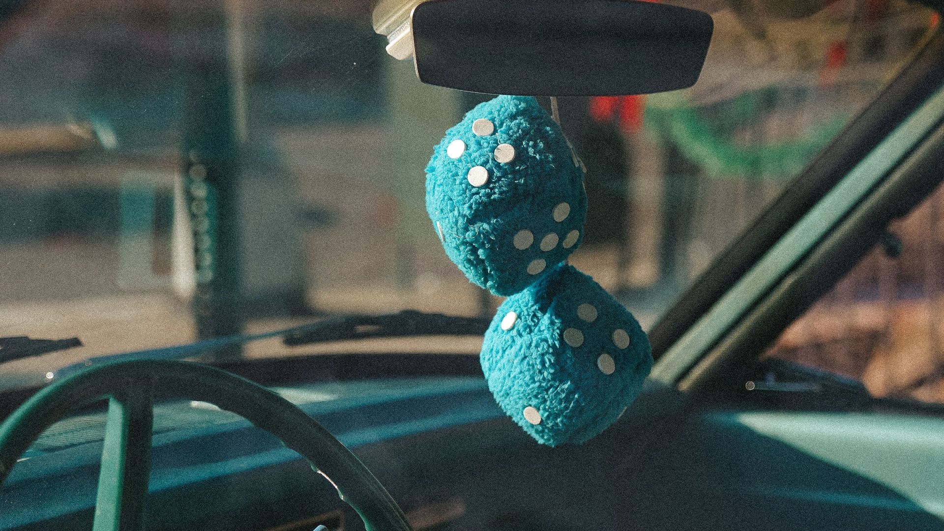 Close-up of blue fuzzy dice hanging from the rearview mirror of a classic car in New York.