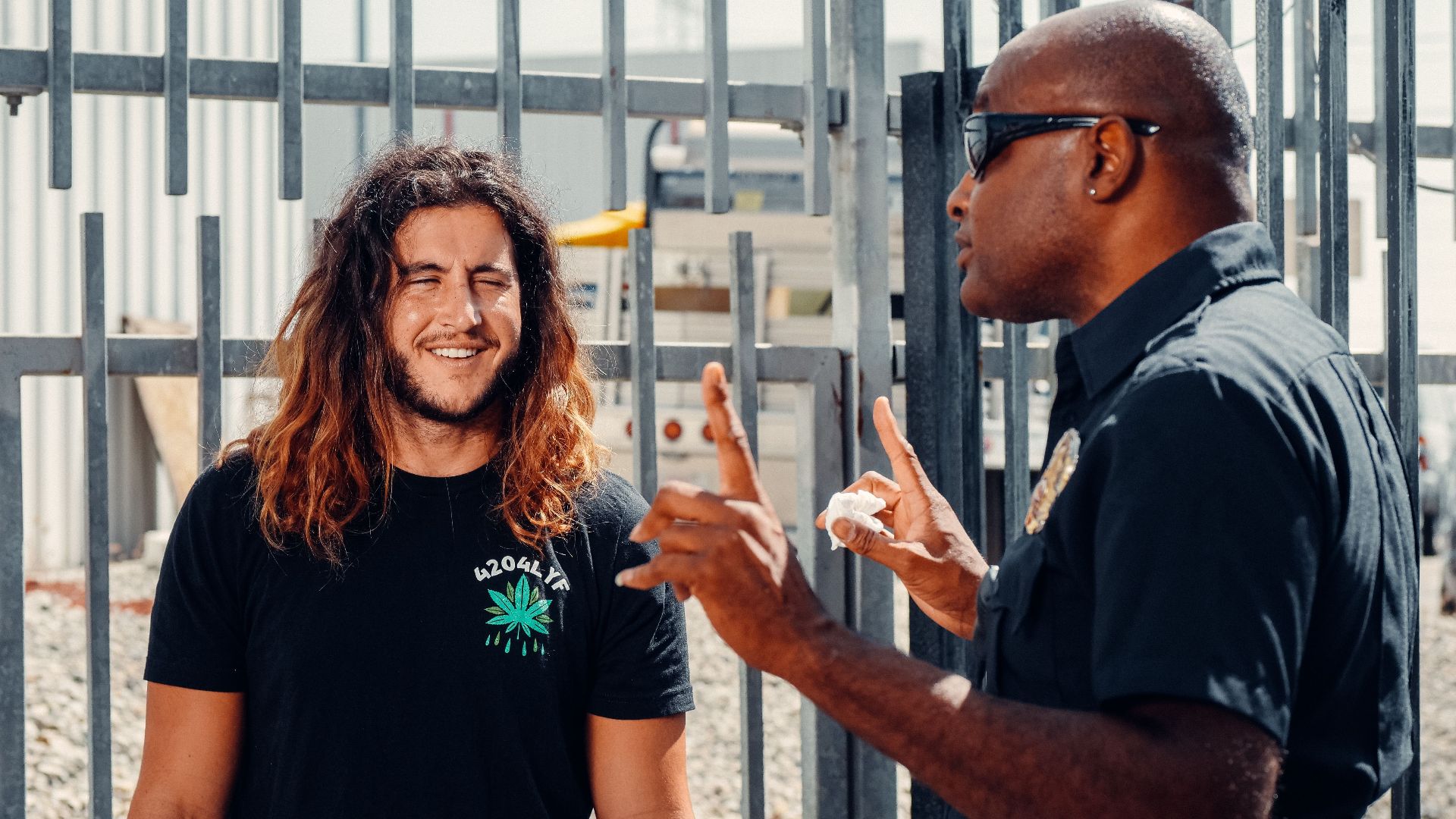A police officer engages in conversation with a civilian outside on a sunny day.
