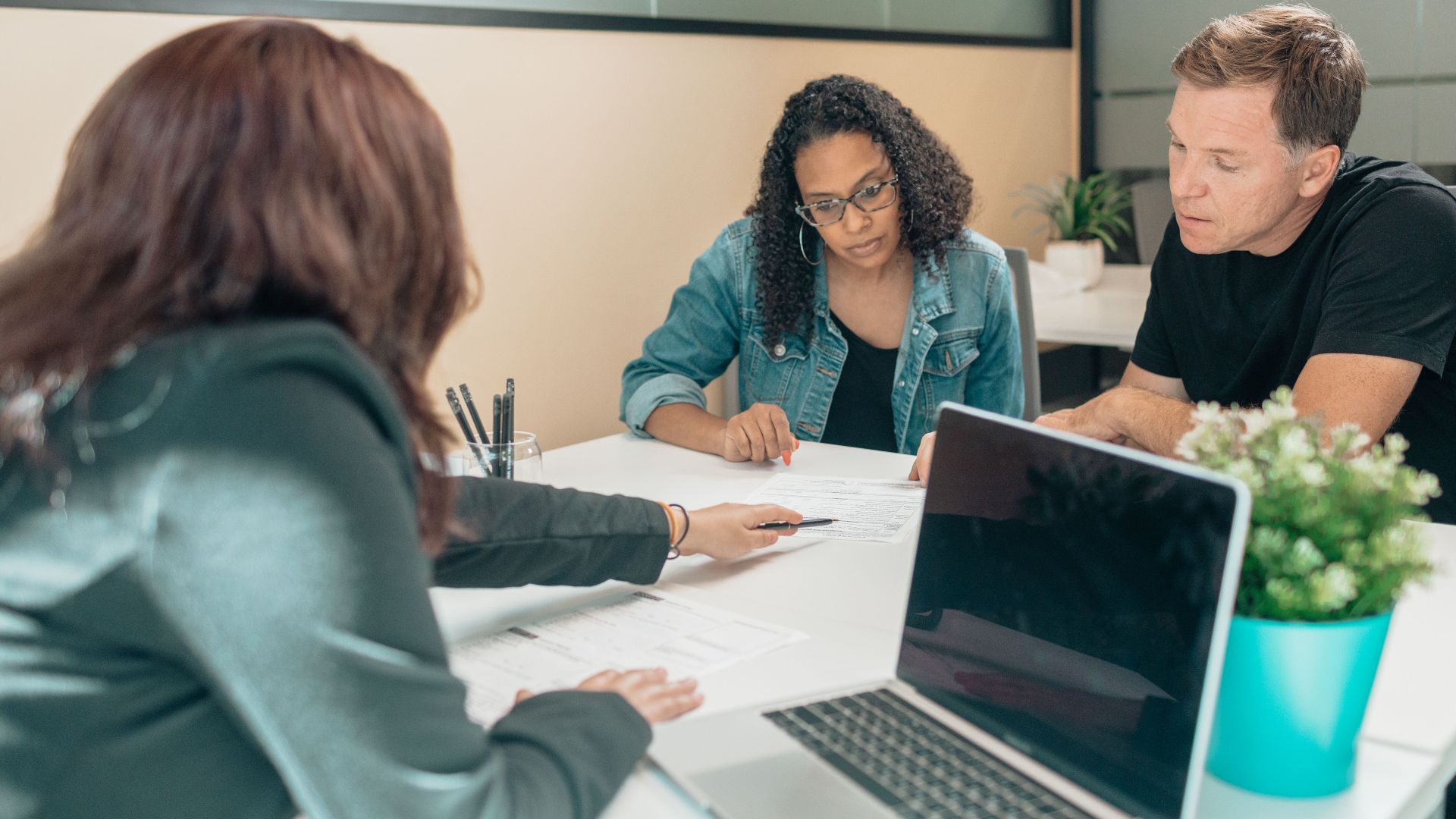Couple meeting with advisor for adoption process in a modern office setting.