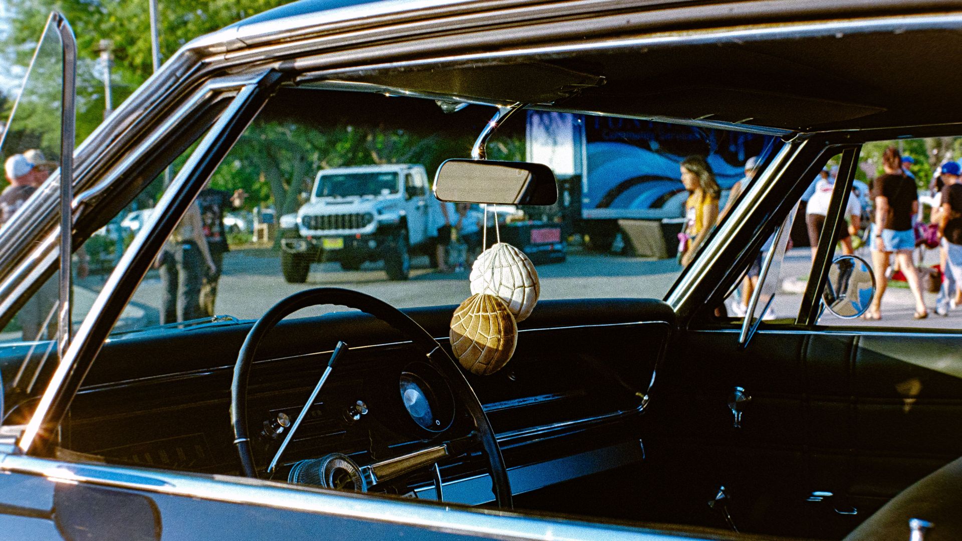 Interior of a classic car parked outdoors, showcasing vintage design elements and event atmosphere.