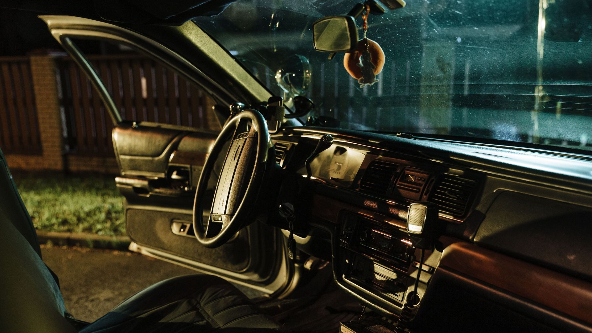 Stylish car interior shot at night with open door, highlighting steering wheel and seats.