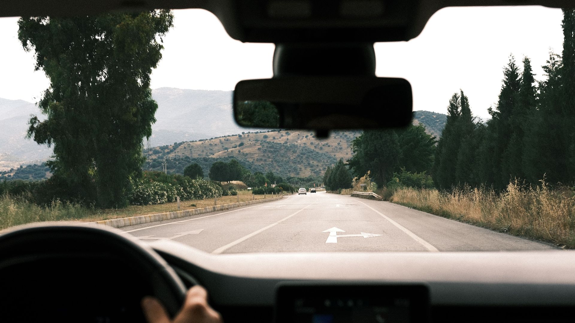 View from inside a car driving on a scenic, mountainous road during daytime.