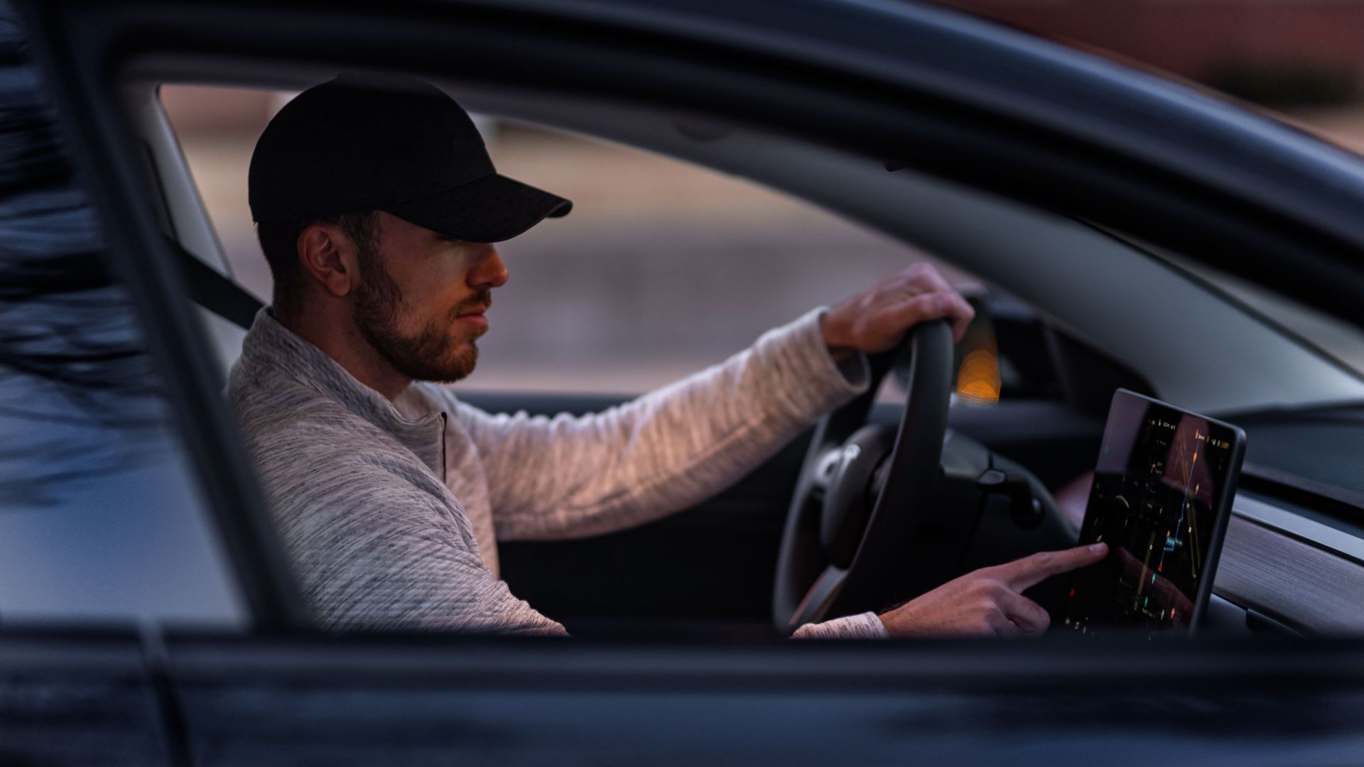 A man interacts with a touchscreen inside an electric car, driving through Dallas, TX.