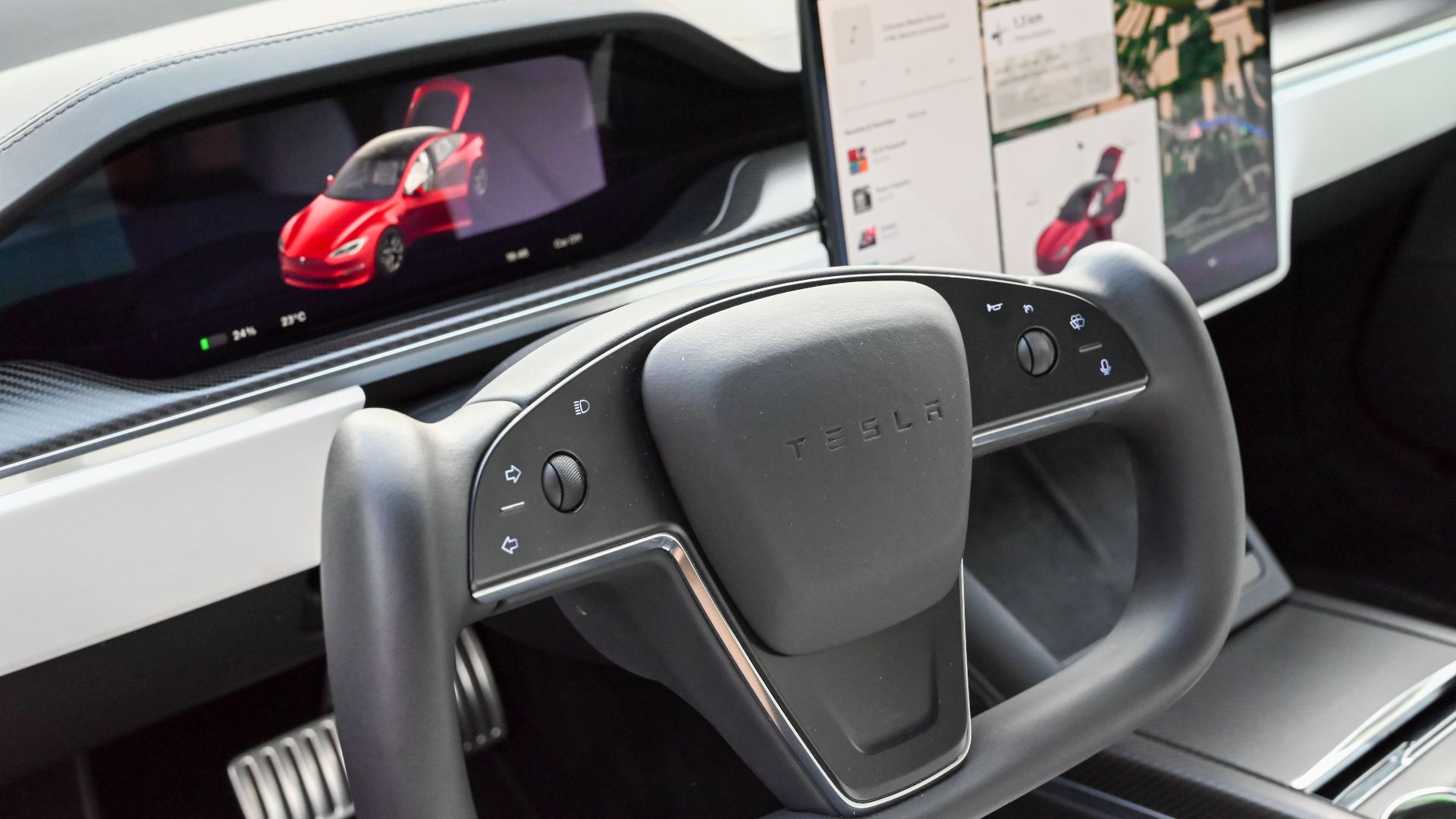 Modern Tesla car interior featuring a steering yoke and digital displays showcasing features.