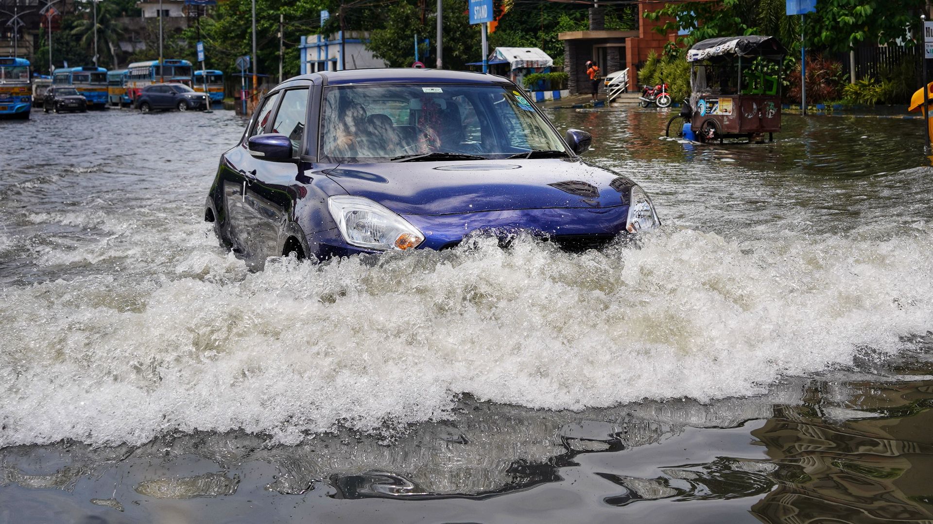 A blue car drives through flooded streets in Kolkata, India after heavy rain.
