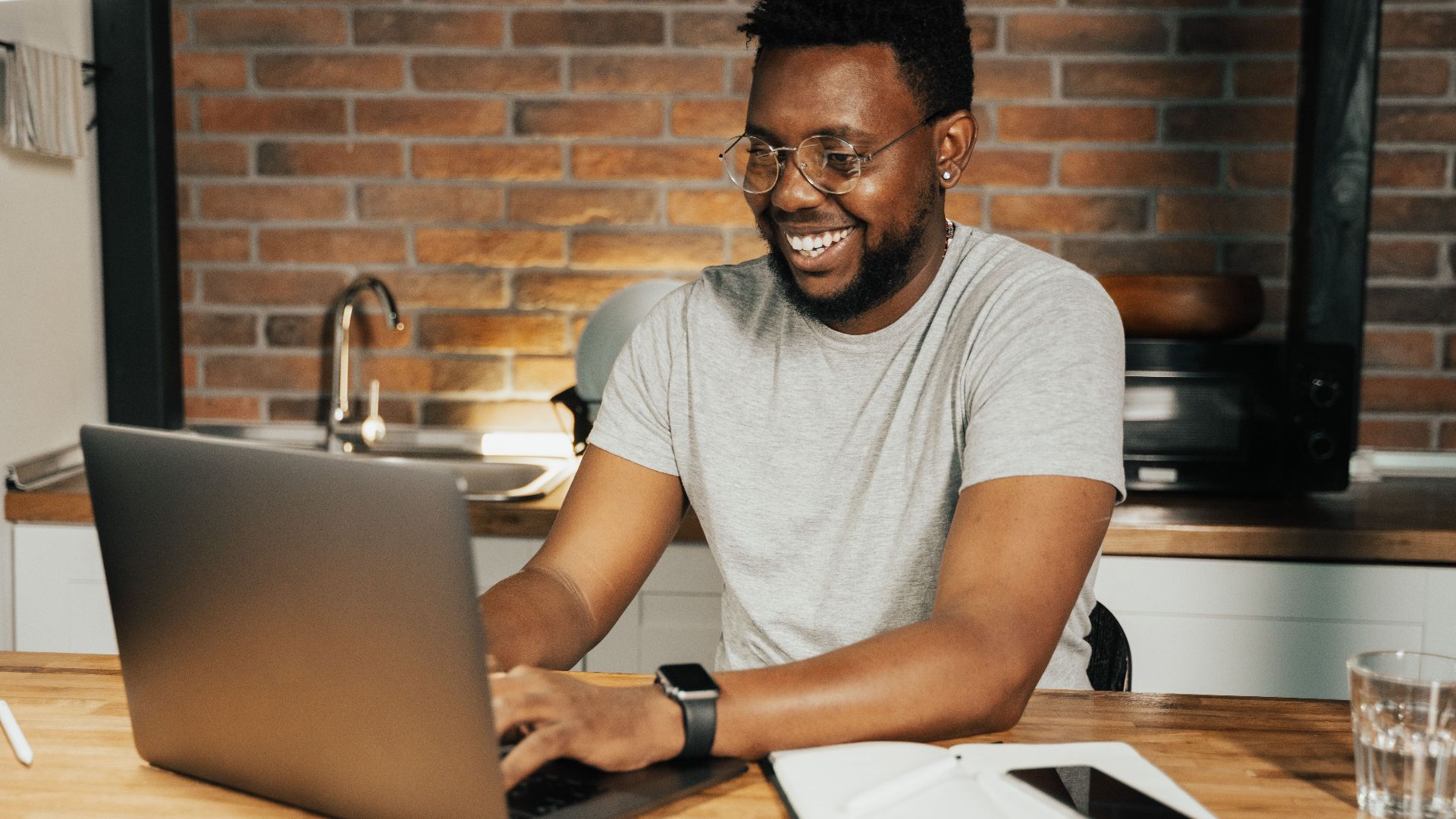 African American man smiling while working remotely on laptop from home office