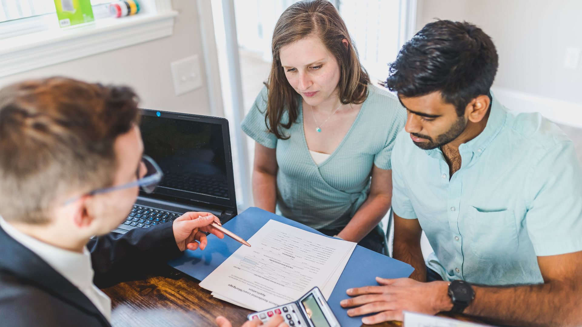 Young couple meeting with real estate agent to discuss property purchase.