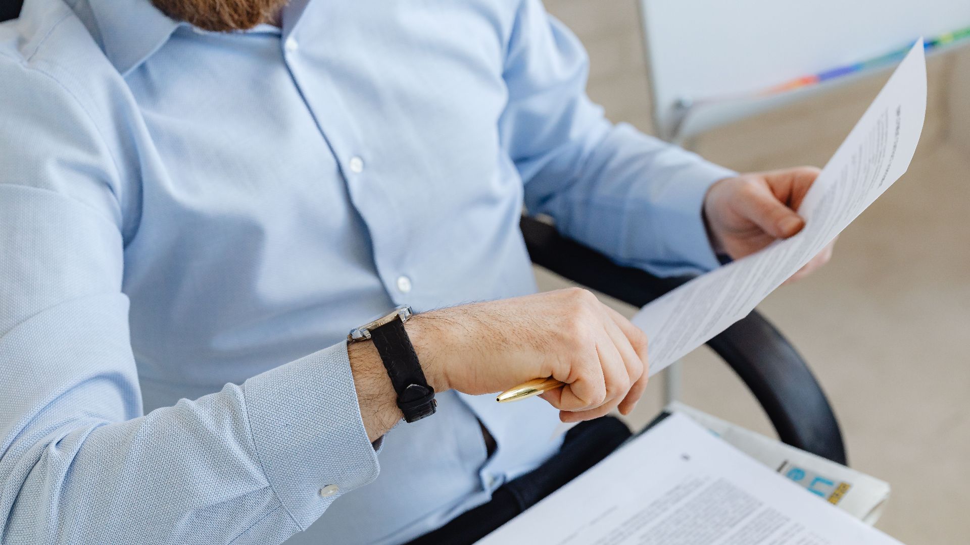 Businessman reviewing papers in office setting, highlighting analysis and attention to detail.