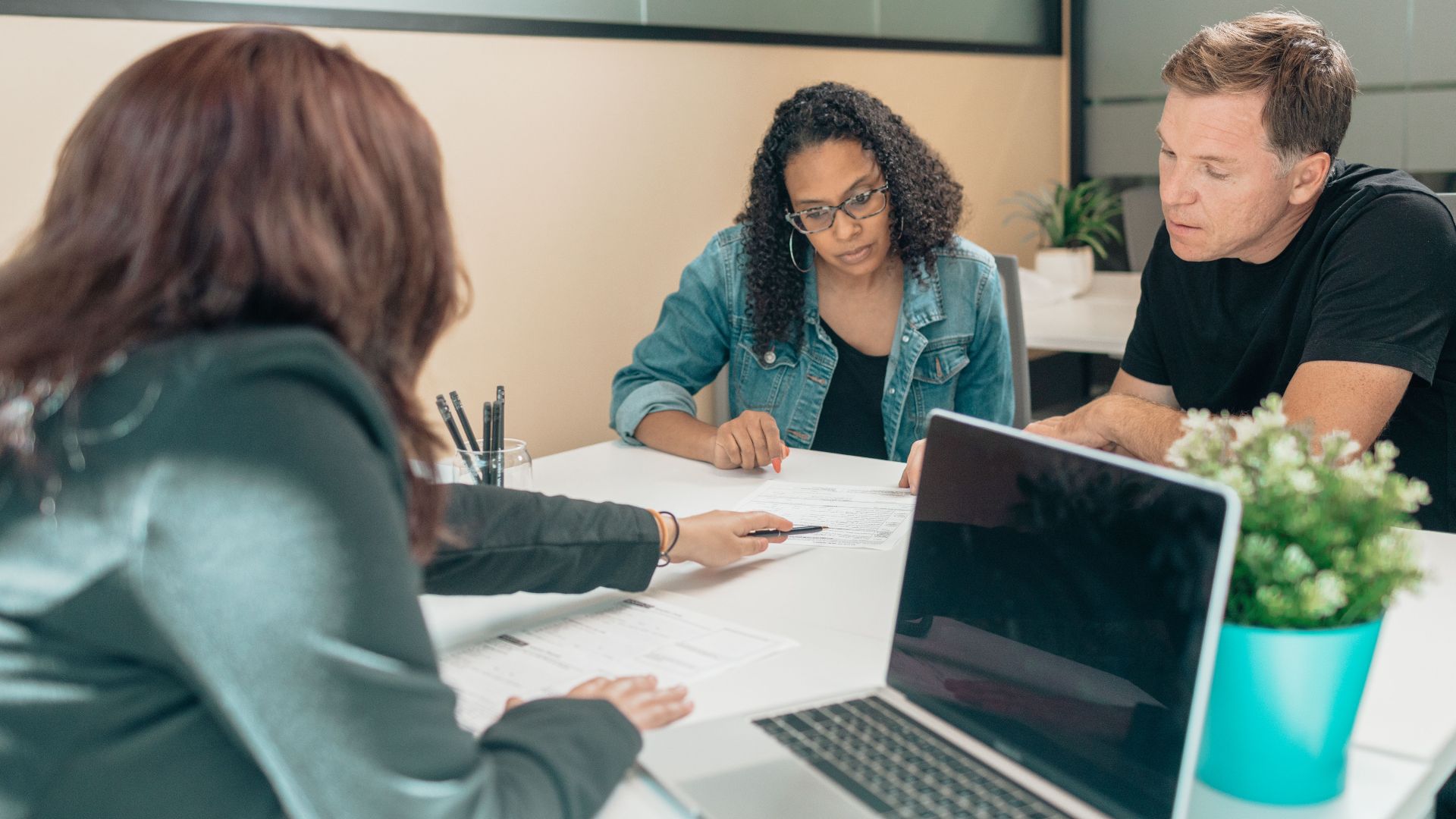 Couple meeting with advisor for adoption process in a modern office setting.
