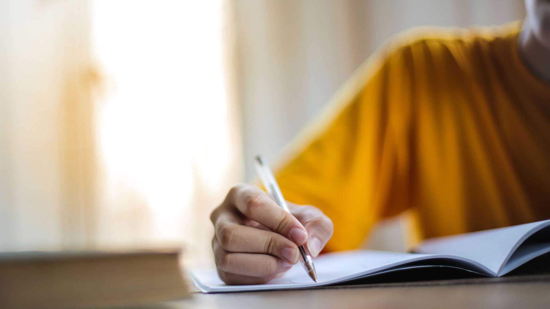 Close-up of a person writing in a notebook, symbolizing focus and learning.