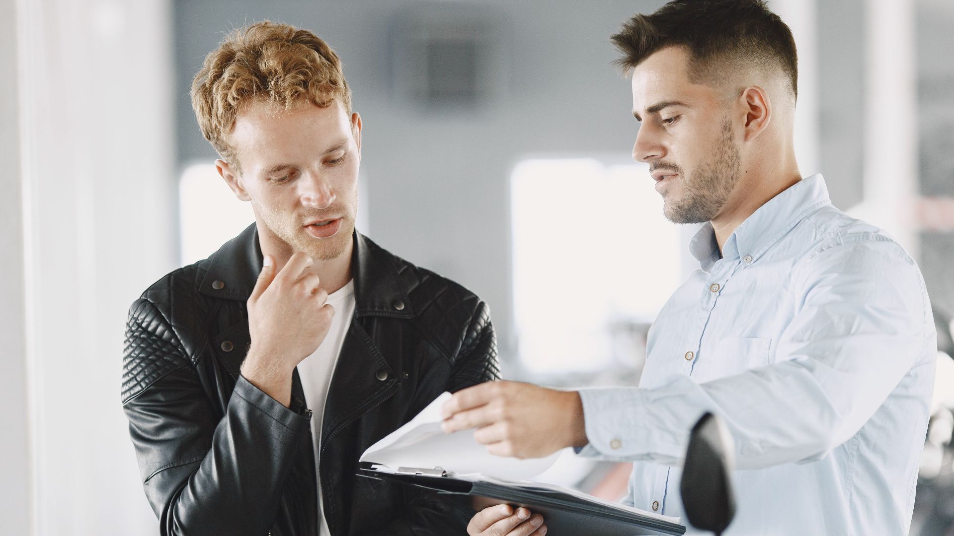 Two adults discussing purchasing options at a motorcycle dealership.