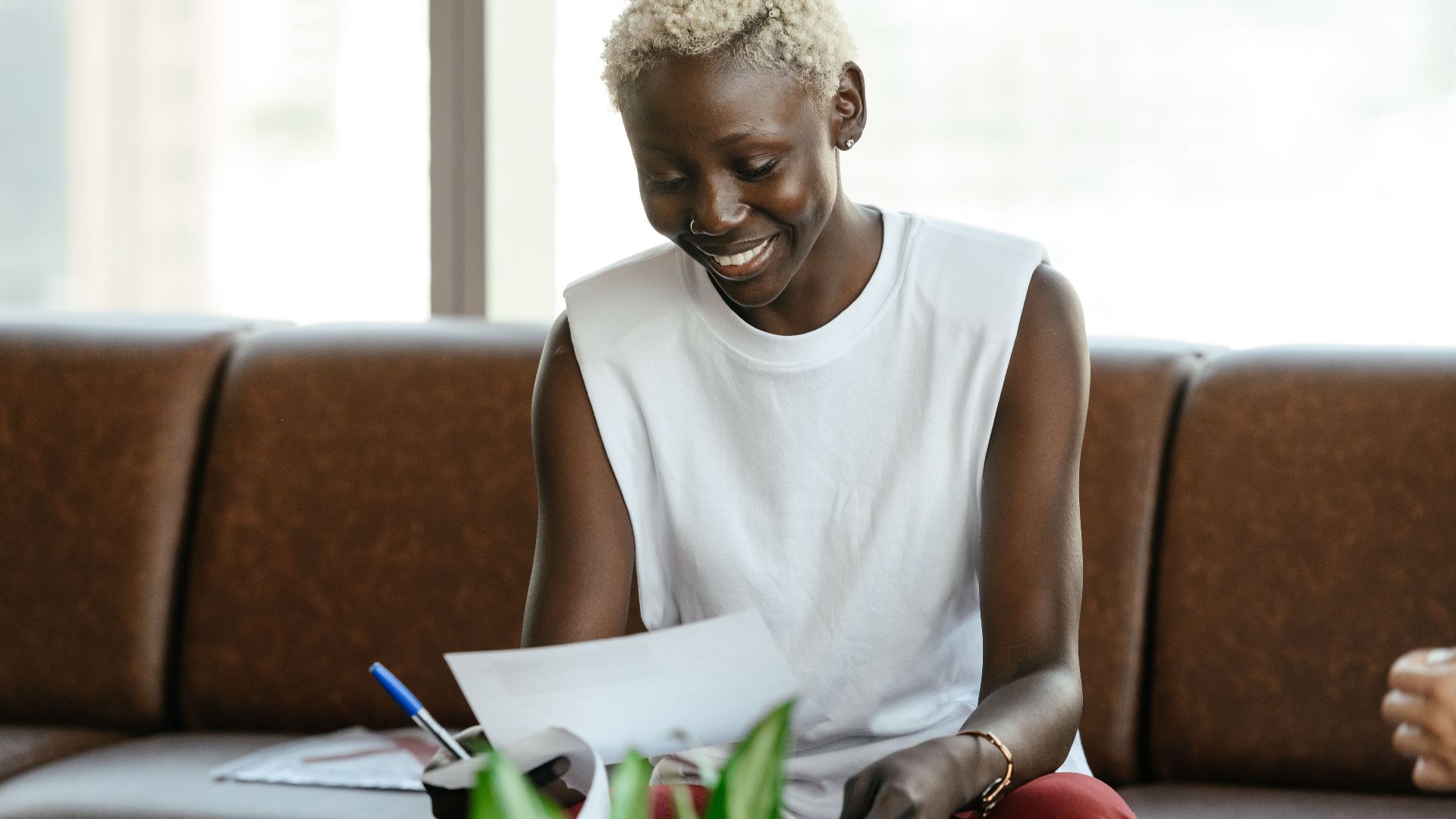 Cheerful young African American female reading document on paper in comfortable office in daytime