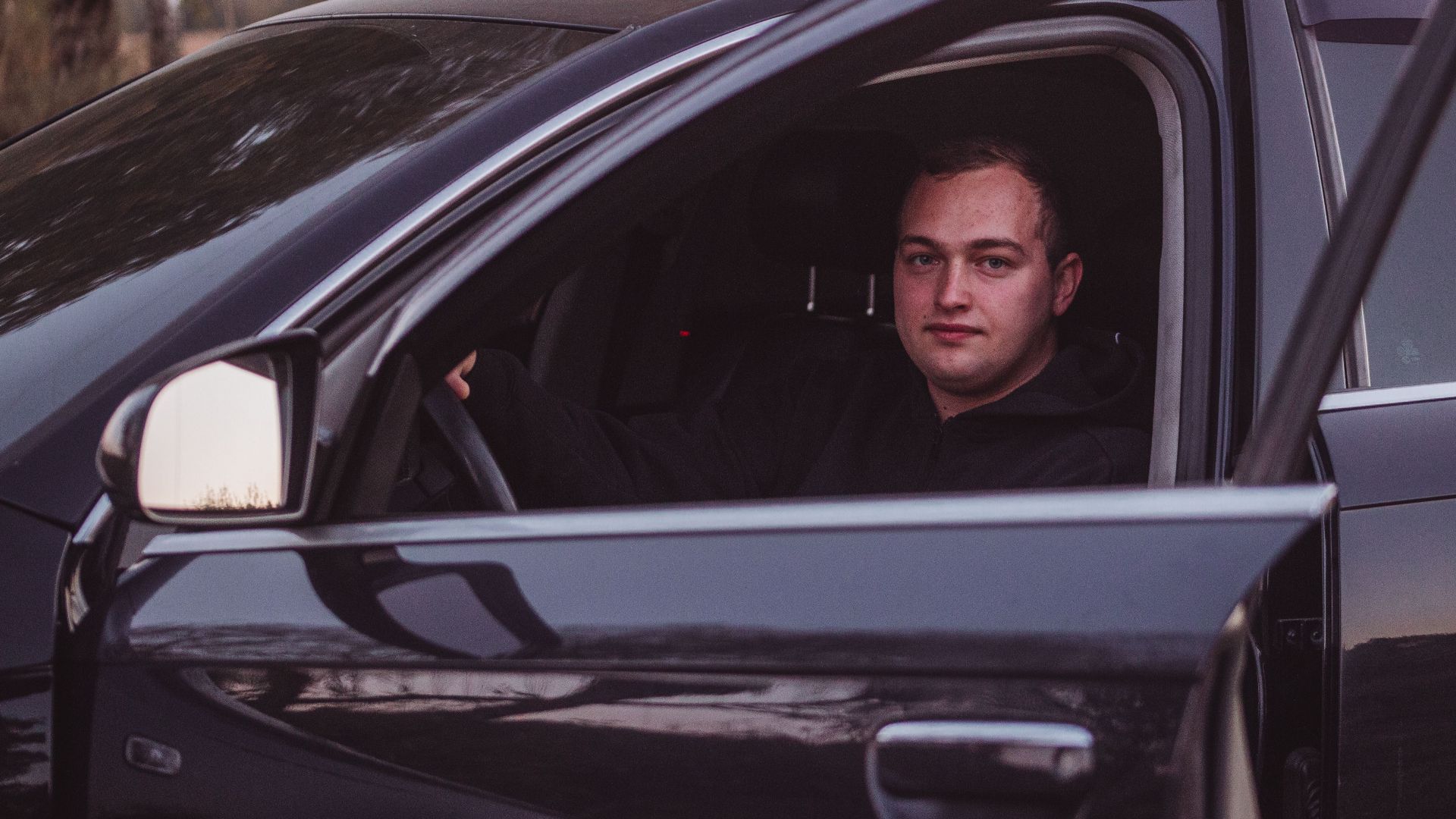 Male driver in a parked car during twilight, capturing a serene moment.