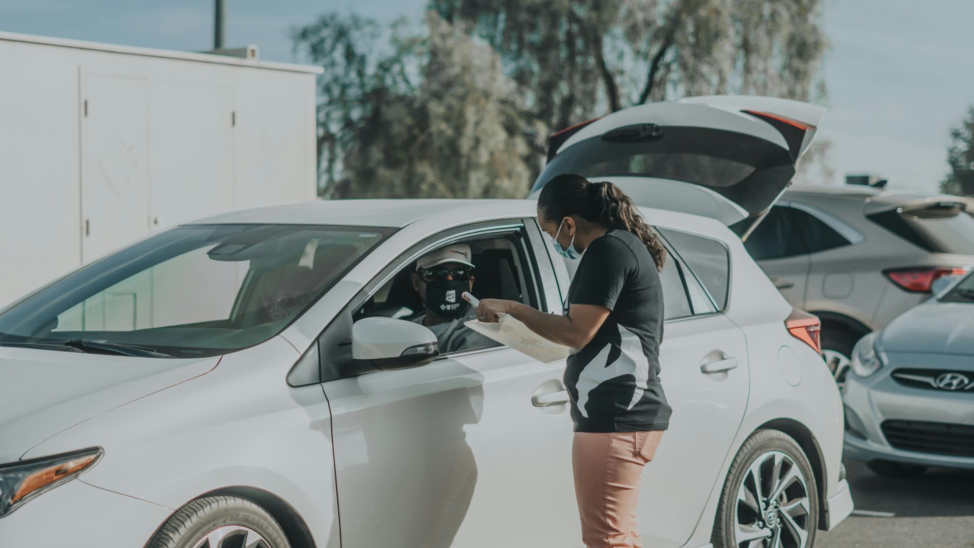 woman in black and white shirt and orange shorts leaning on white car during daytime