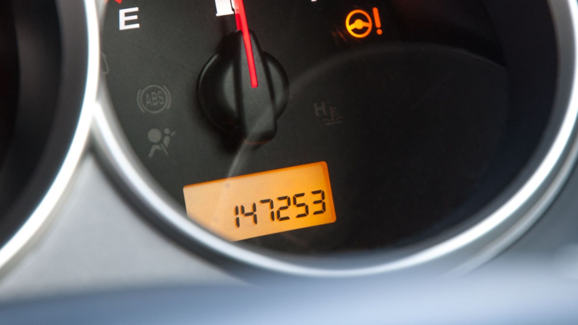 Detailed close-up of a car's fuel gauge with odometer showing a reading of 147253 miles.